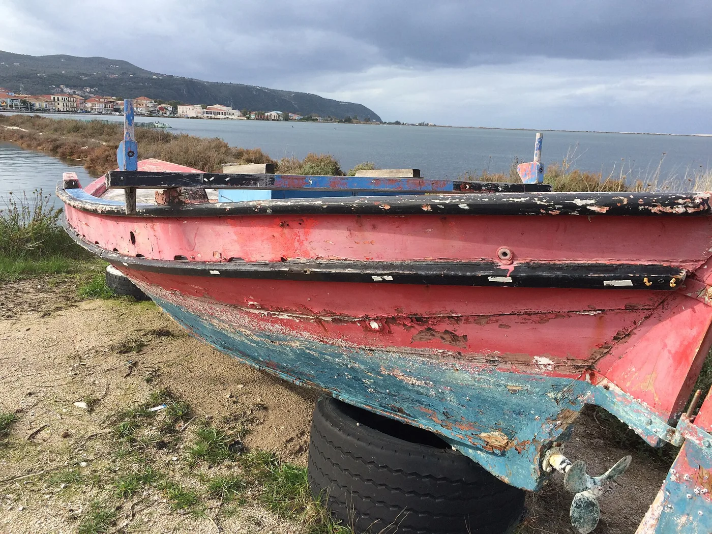 Une vieille barque sur la rive de la lagune, avec la ville de Lefkada au loin