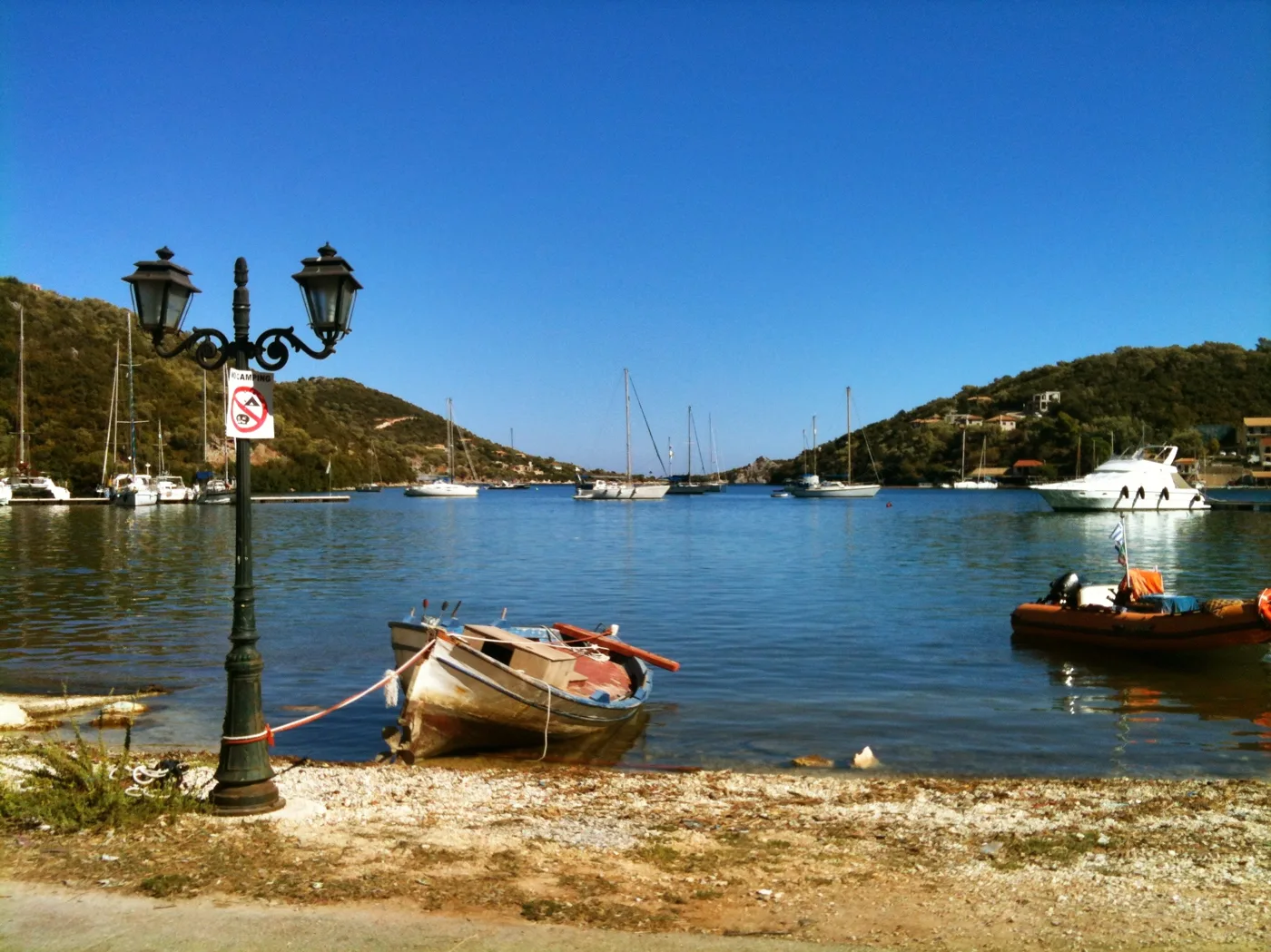 La baie de Sivota avec des bateaux, un lampadaire et des collines vertes