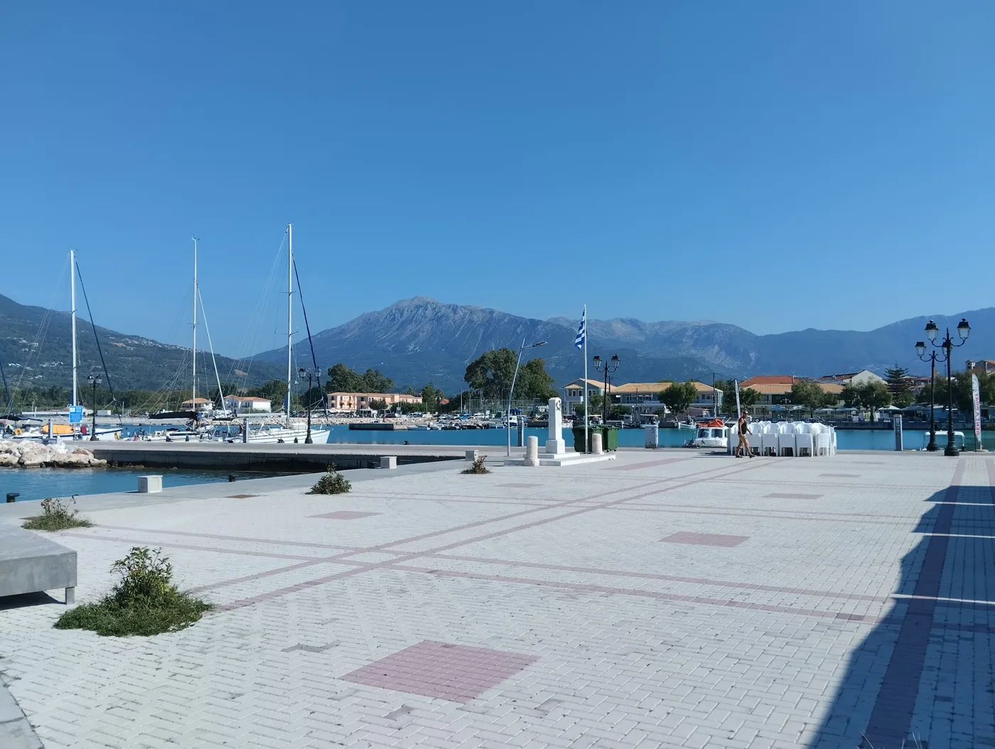 Le port de Vasiliki avec des voiliers, un quai pavé et des montagnes