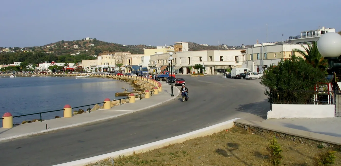 Il viale del lungomare di Lakki con palme e bassi edifici bianchi