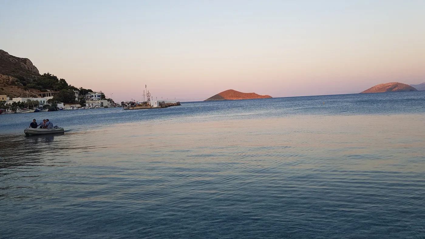 La baia di Panteli al tramonto, con una barca e isolotti in lontananza