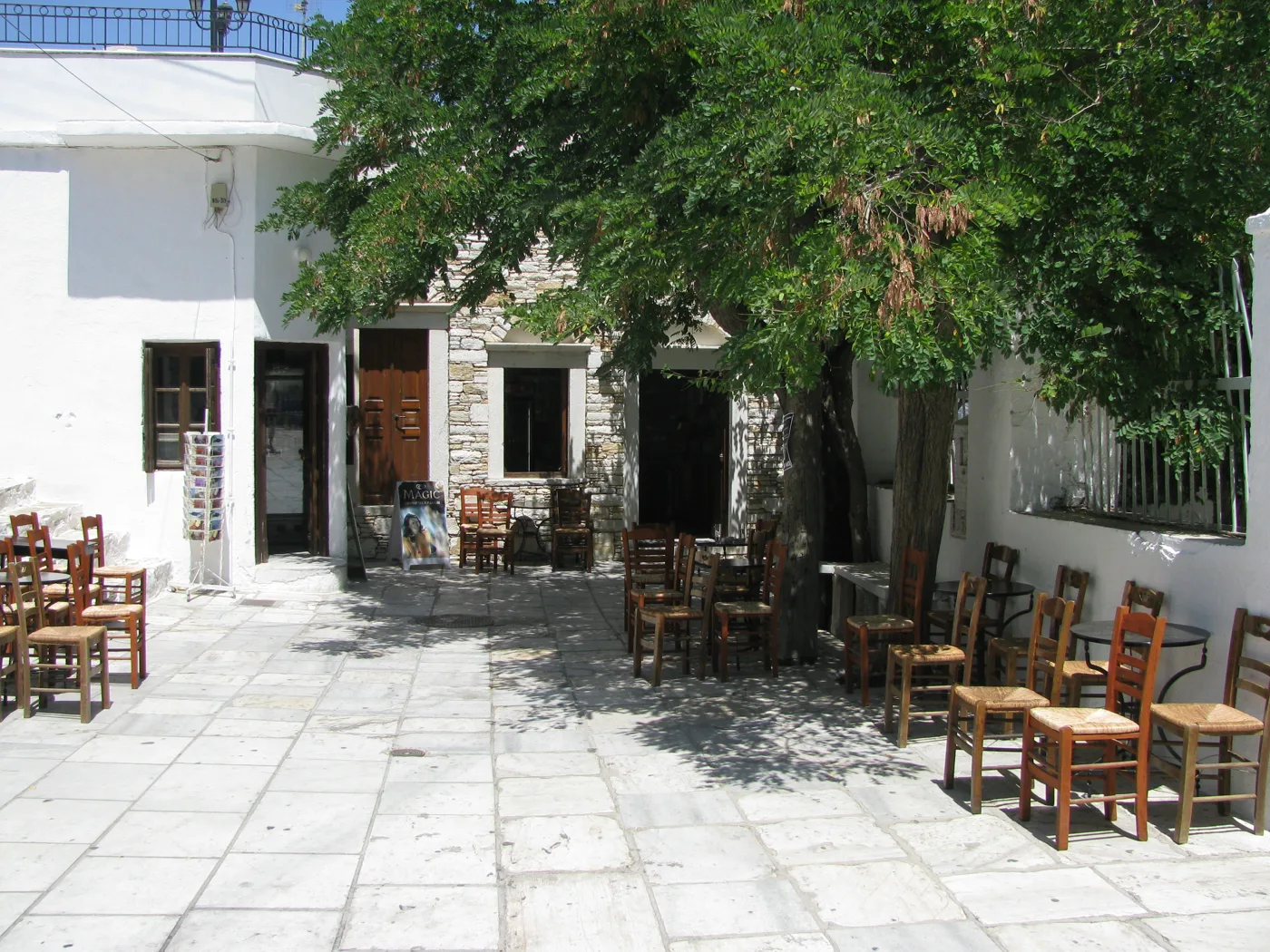 Μικρή πλατεία στην Απείρανθο με πέτρινα σπίτια, καρέκλες και ένα δέντρο