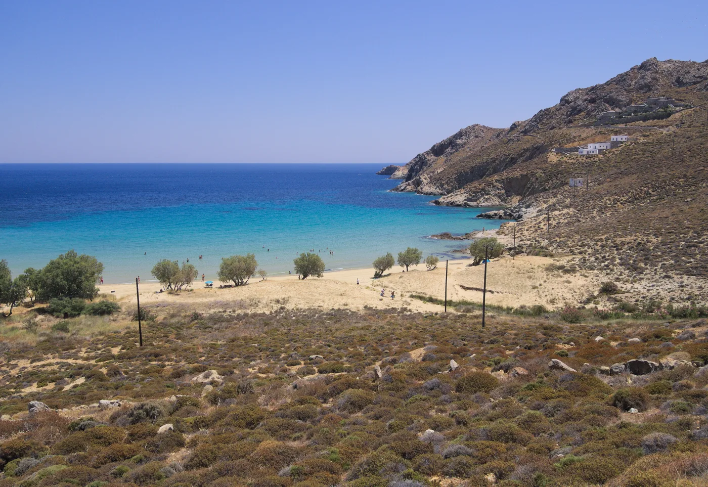 Η αμμουδιά της Ψιλής Άμμου με γαλάζια νερά, αλμυρίκια και λόφους γύρω