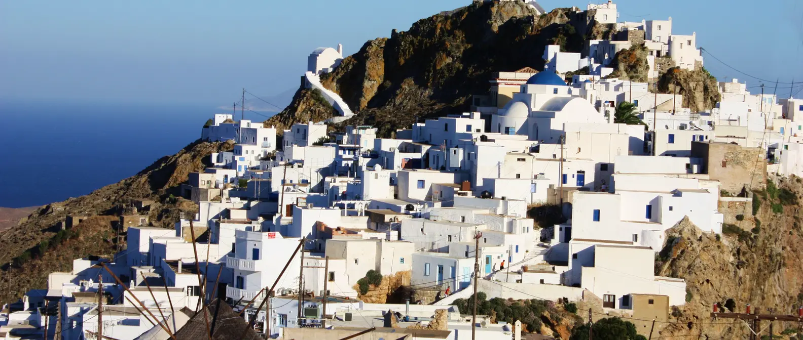 Τα λευκά σπίτια της Χώρας της Σερίφου σκαρφαλωμένα στον λόφο, με έναν ανεμόμυλο στην κορυφή