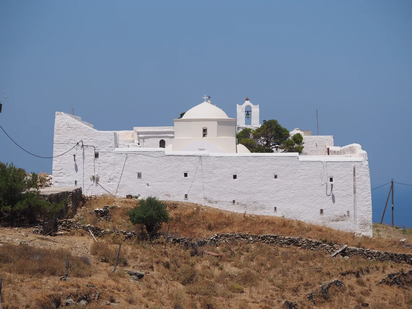 Η λευκή οχυρωμένη Μονή των Ταξιαρχών μέσα σε ξερά χωράφια