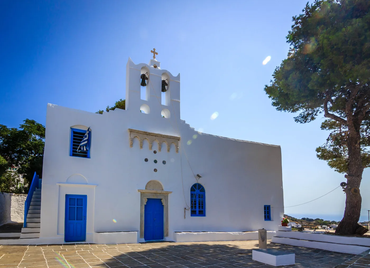 Eine weiße Kirche mit blauen Türen und Glockenturm in Artemonas