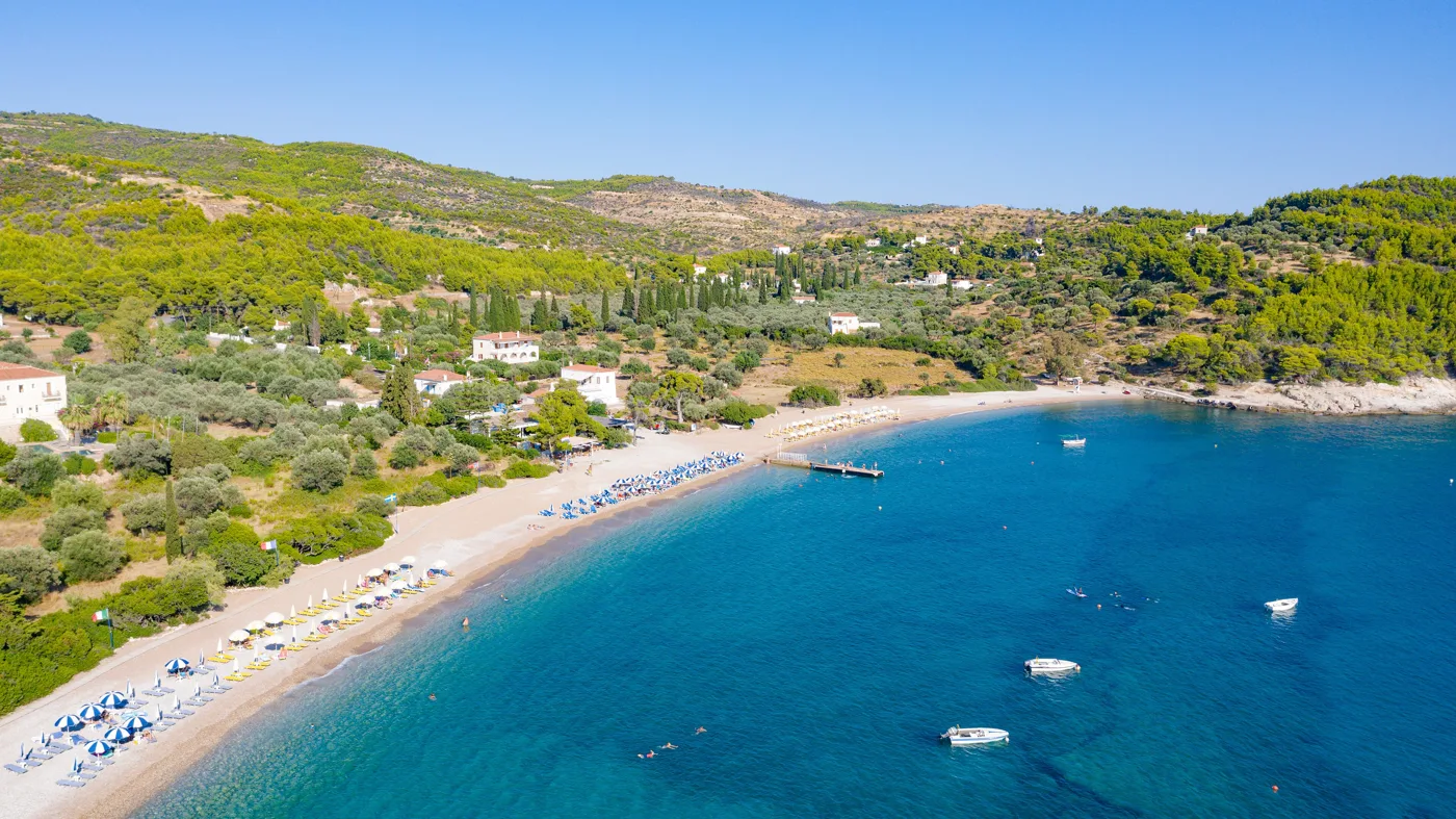 Η παραλία των Αγίων Αναργύρων από ψηλά, με ξαπλώστρες, πεύκα και γαλάζια νερά