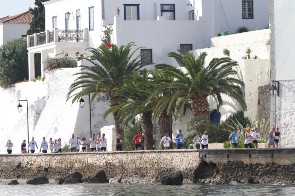 Λευκά σπίτια, ένας φοίνικας και κόσμος στον περίπατο του Παλιού Λιμανιού