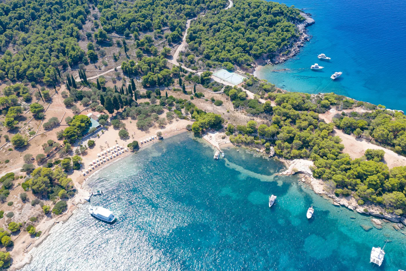 Σκάφη αγκυροβολημένα στα γαλαζοπράσινα νερά της Ζωγεριάς, μέσα στα πεύκα
