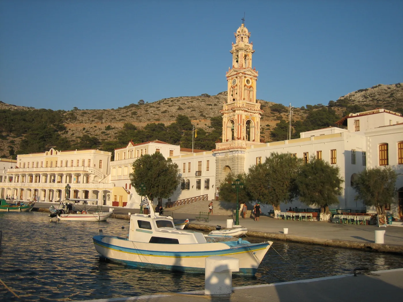 Il monastero di Panormitis con il campanile, dietro una barca nella baia