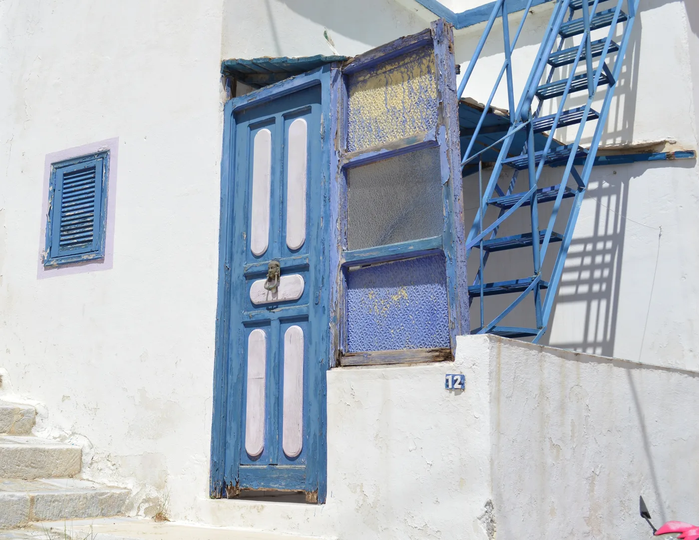 Une porte en bois bleue et un escalier bleu sur une maison blanche à Ano Syros
