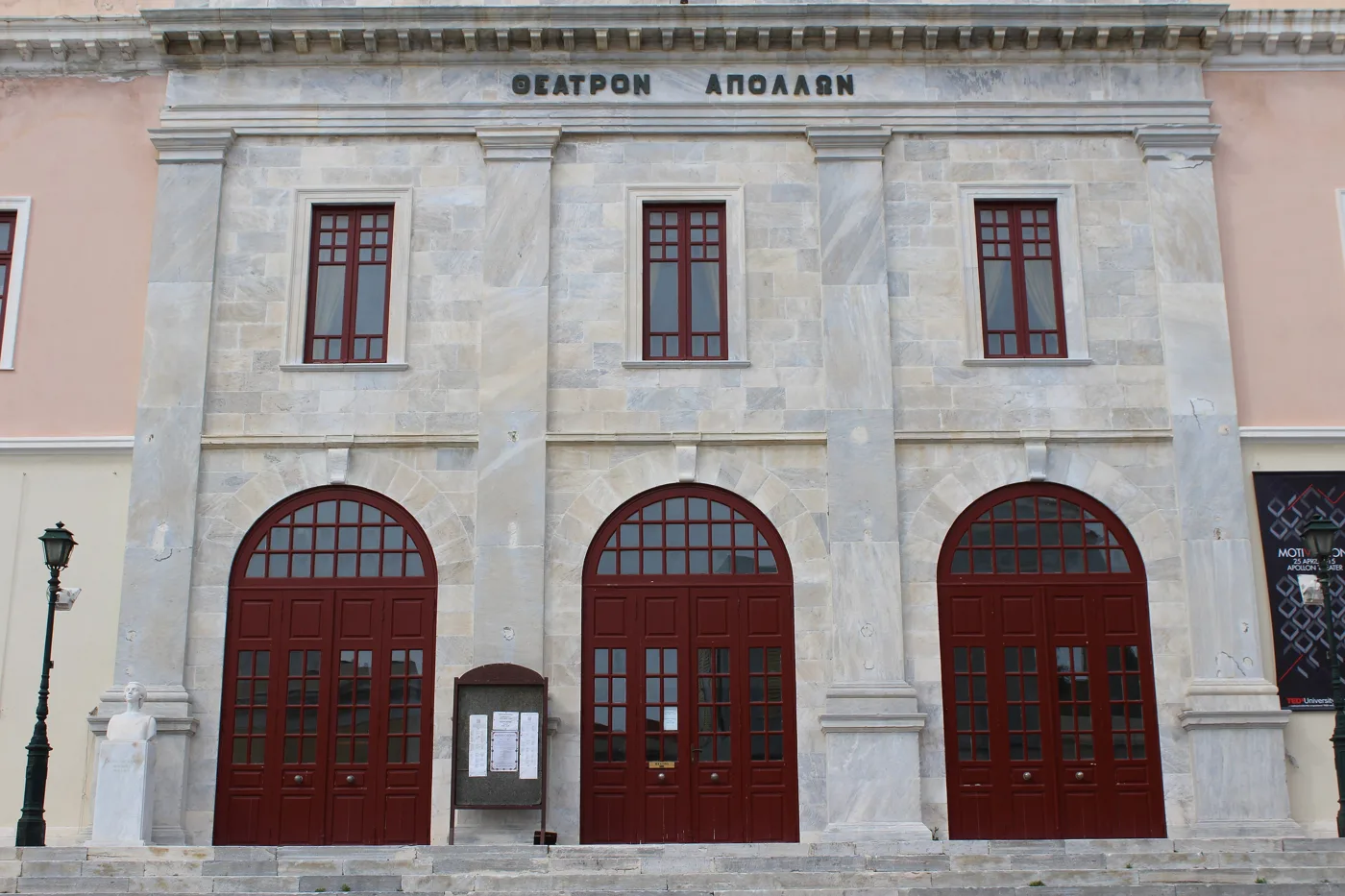 La façade en marbre du théâtre Apollon avec trois portes rouges