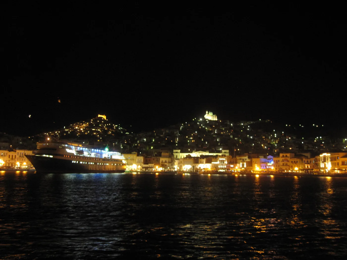 Ermoupoli la nuit, avec des lumières sur les collines et un navire dans le port