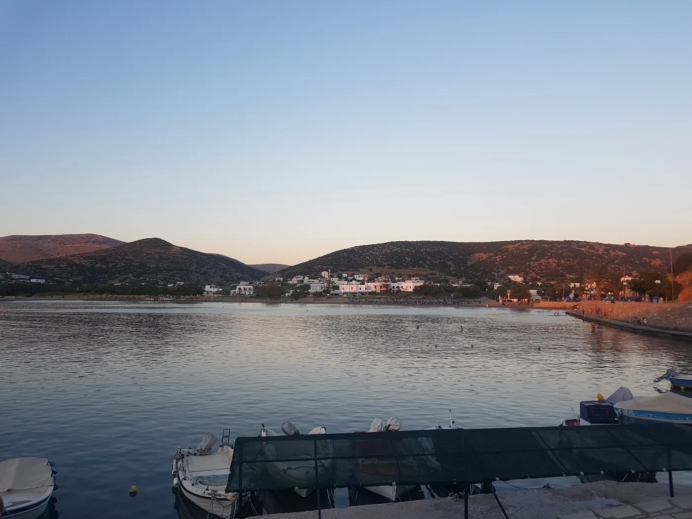 La baie de Galissas au crépuscule, avec des barques et une mer calme