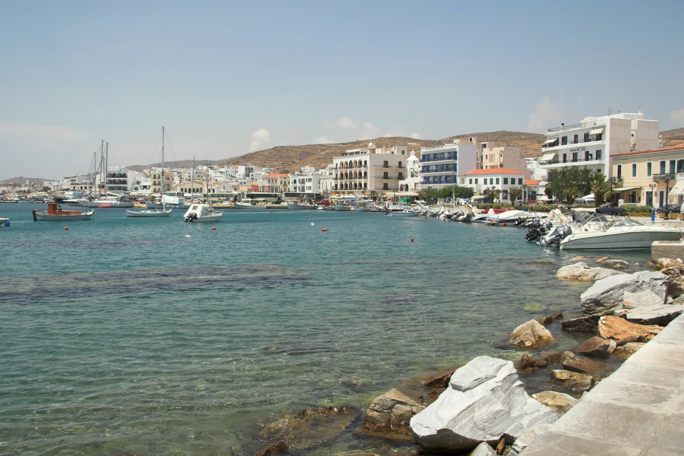 A marginal de Tinos com casas, barcos e água transparente à frente