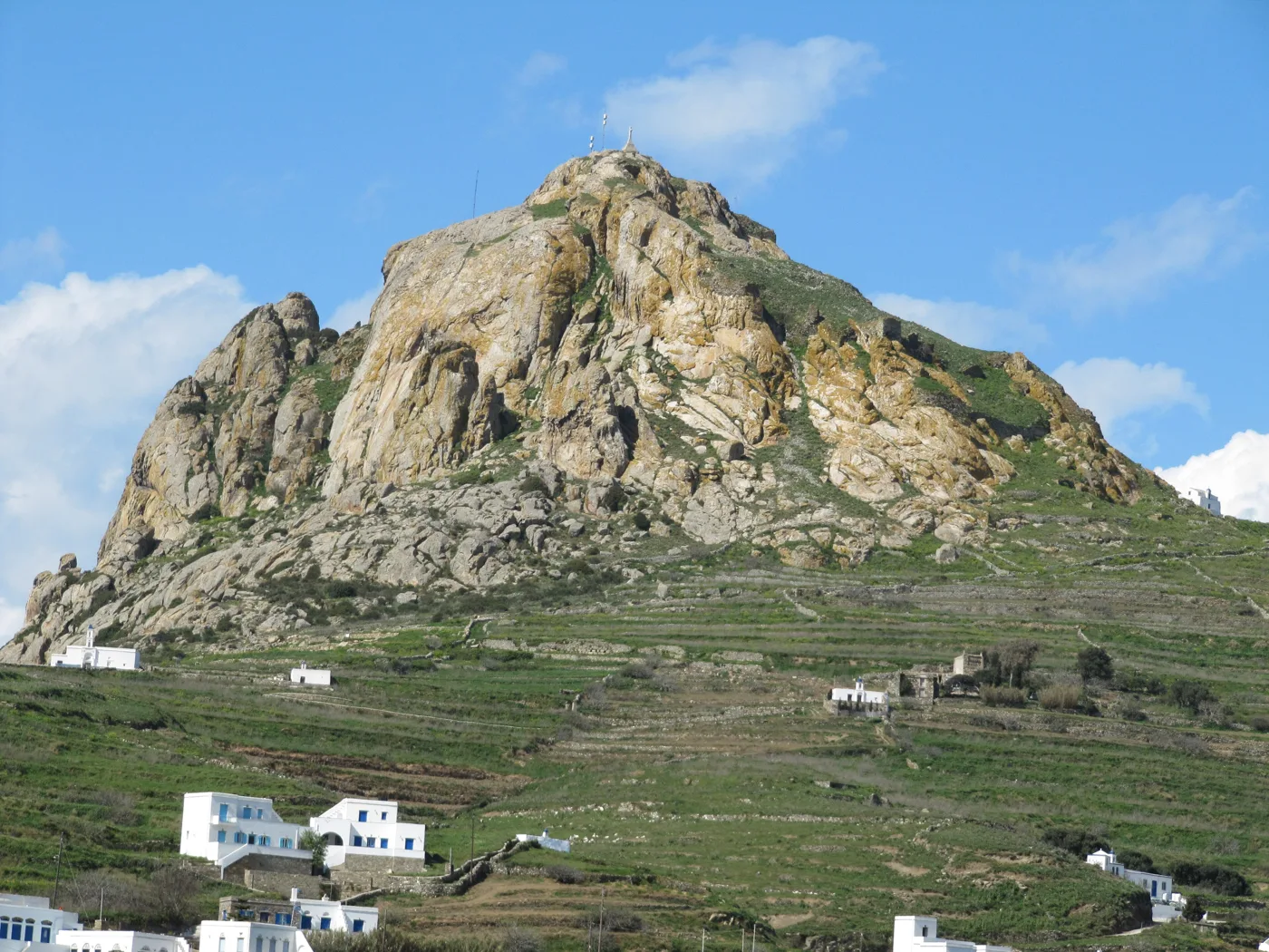 A colina rochosa de Exomvourgo por cima de socalcos verdes e casas brancas