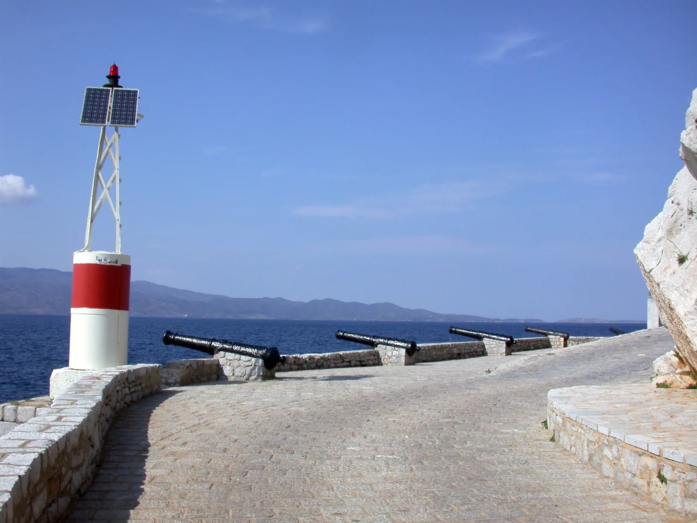 De vieux canons sur le bastion au bout du port, avec un phare