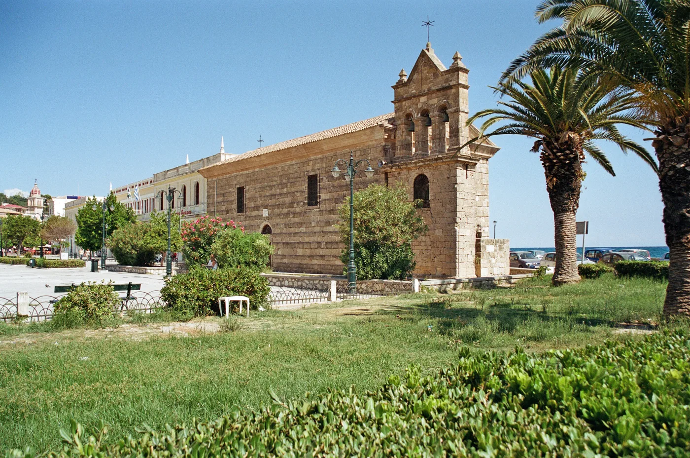 The stone church of Agios Nikolaos tou Molou with its bell tower, among palm trees