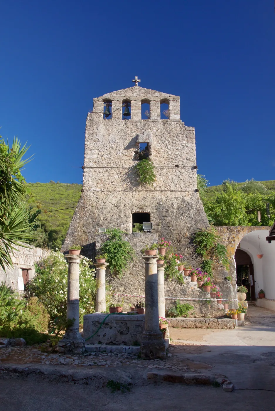 The stone tower and bell tower of the Anafonitria Monastery under a blue sky