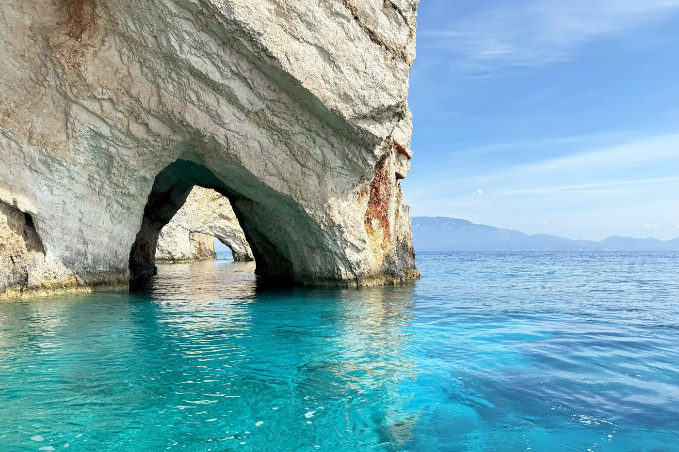 A rock arch over turquoise water at the Blue Caves of Zakynthos