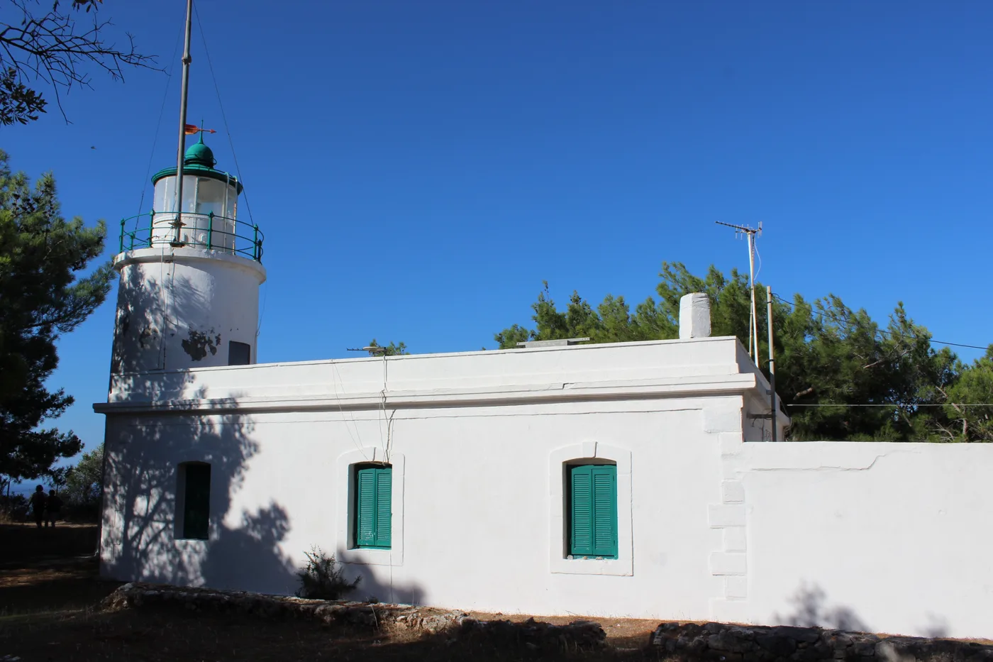 The white lighthouse of Keri with green windows, under a blue sky