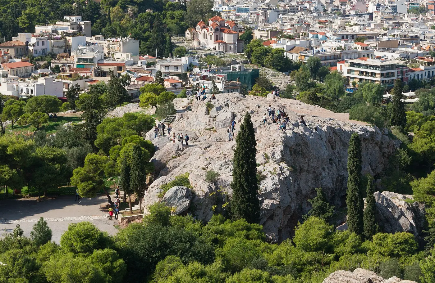 De kale rots van de Areopagus met mensen erop, gezien vanaf de Akropolis