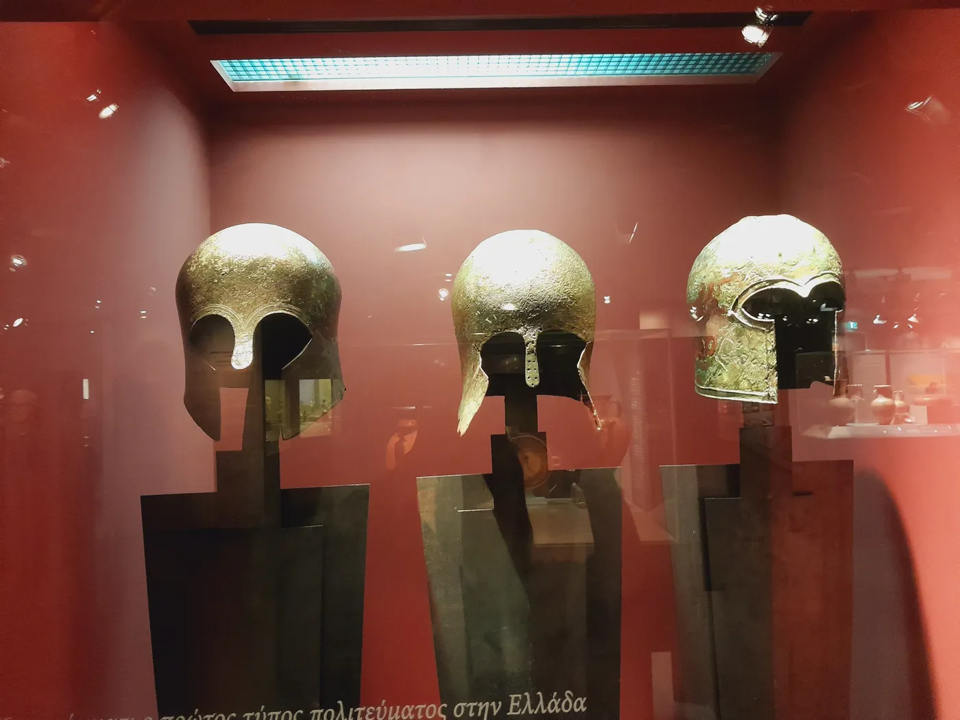 红色展柜里的三顶古代青铜头盔