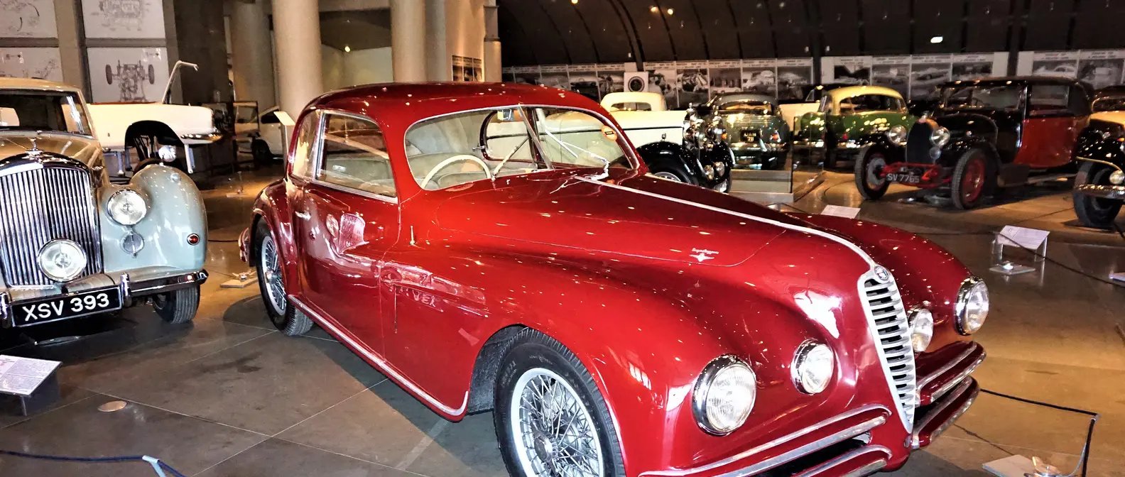Un’auto d’epoca rossa tra modelli storici nella sala del Museo ellenico dell’automobile, uno dei musei per bambini ad Atene