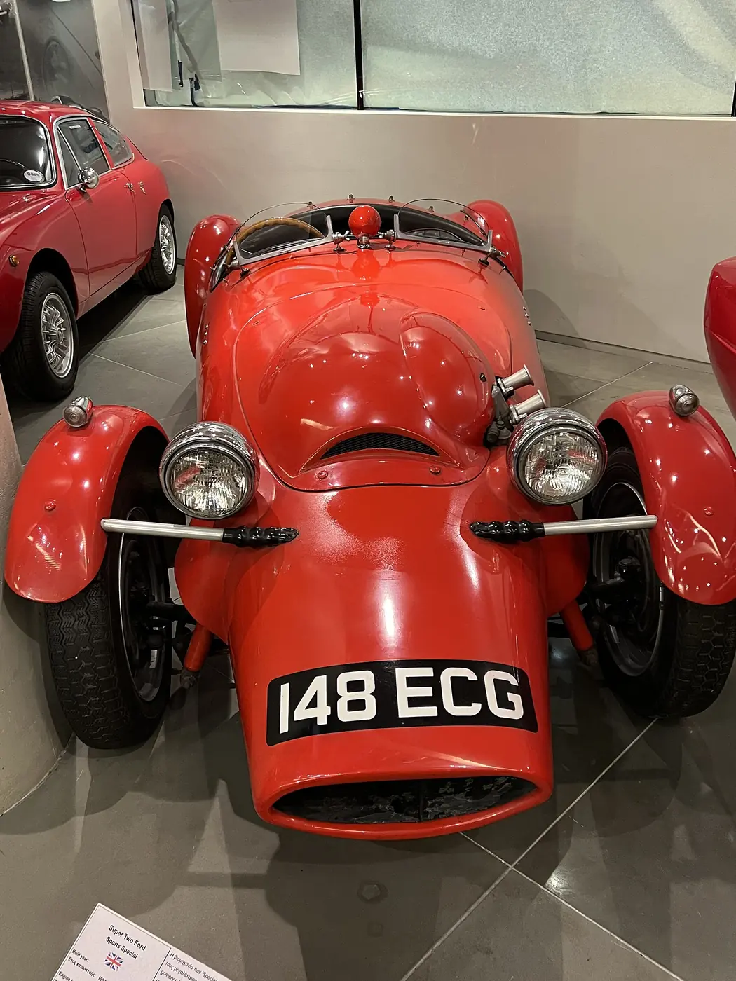 Una piccola auto da corsa rossa con targa britannica, vista di fronte, al Museo dell’automobile