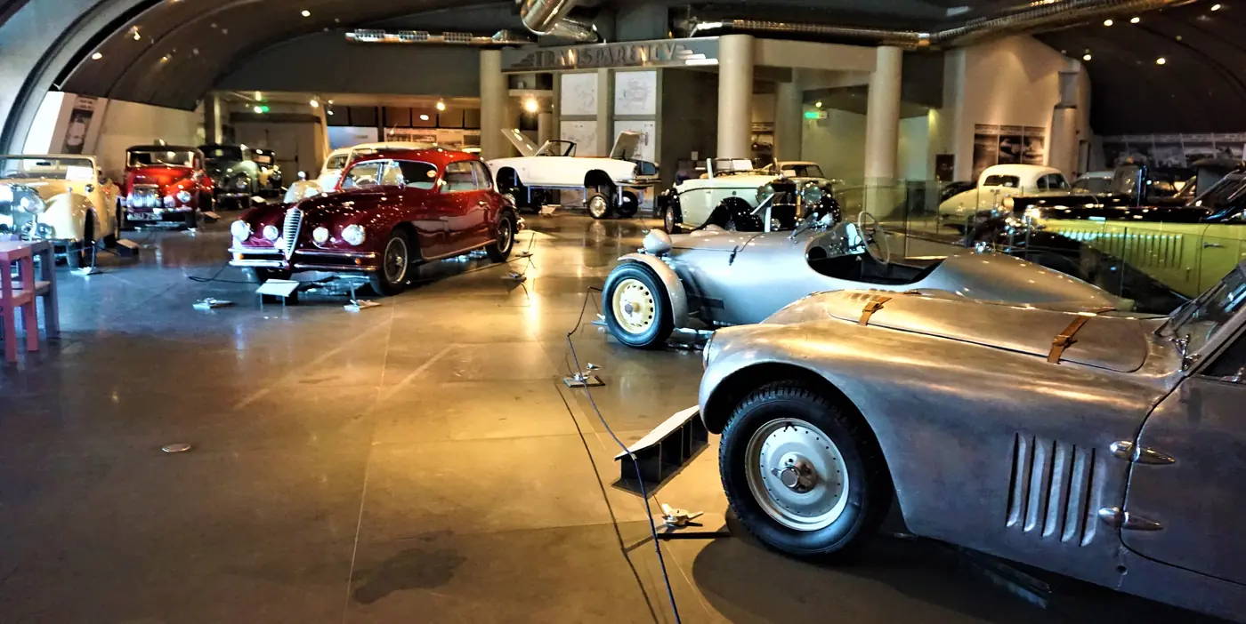 La sala del Museo ellenico dell’automobile con auto d’epoca argento e rosse sotto un soffitto curvo