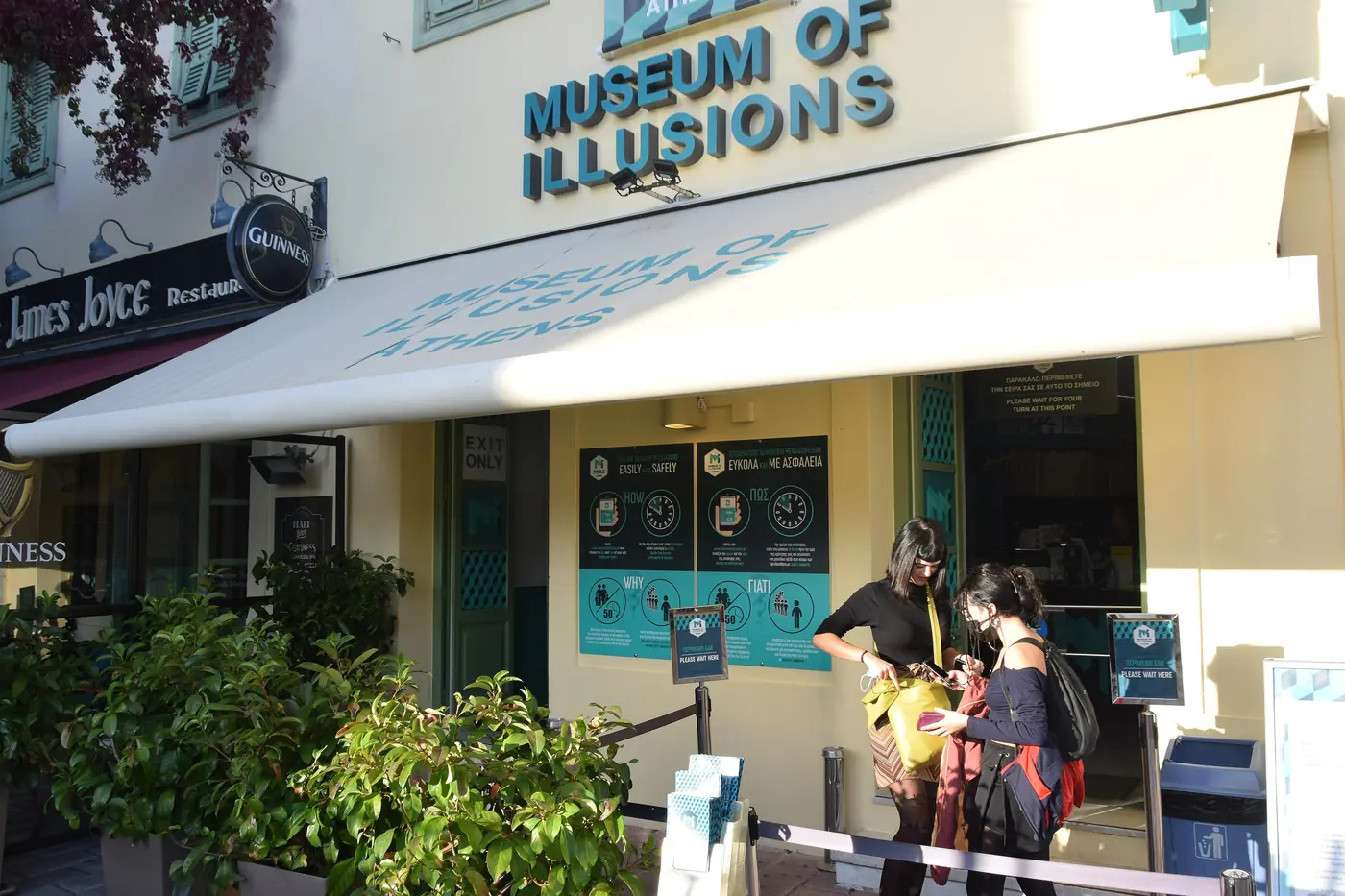 L’ingresso del Museo delle Illusioni a Monastiraki, con la tenda bianca e visitatori sul marciapiede