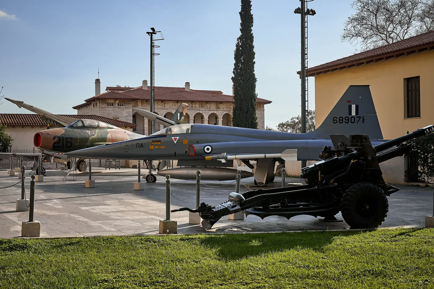 Il cortile del Museo della Guerra con un cannone, aerei e cipressi nella luce del pomeriggio