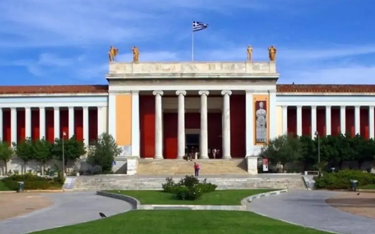 The neoclassical façade of the National Archaeological Museum with its Ionic columns and the palm trees of the garden