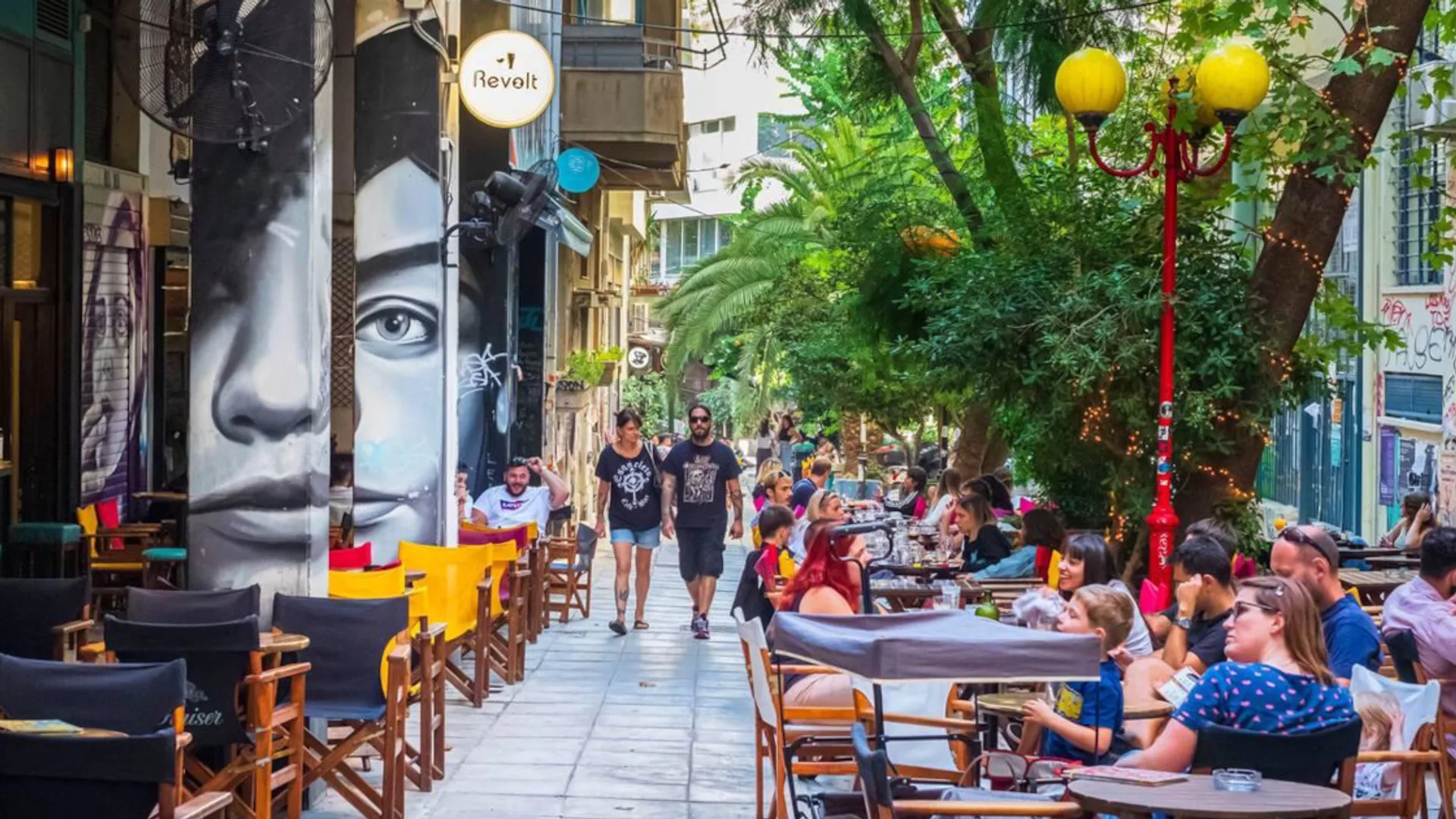 Δρόμος των Εξαρχείων με γκράφιτι και καφέ στα τραπεζάκια του πεζοδρομίου