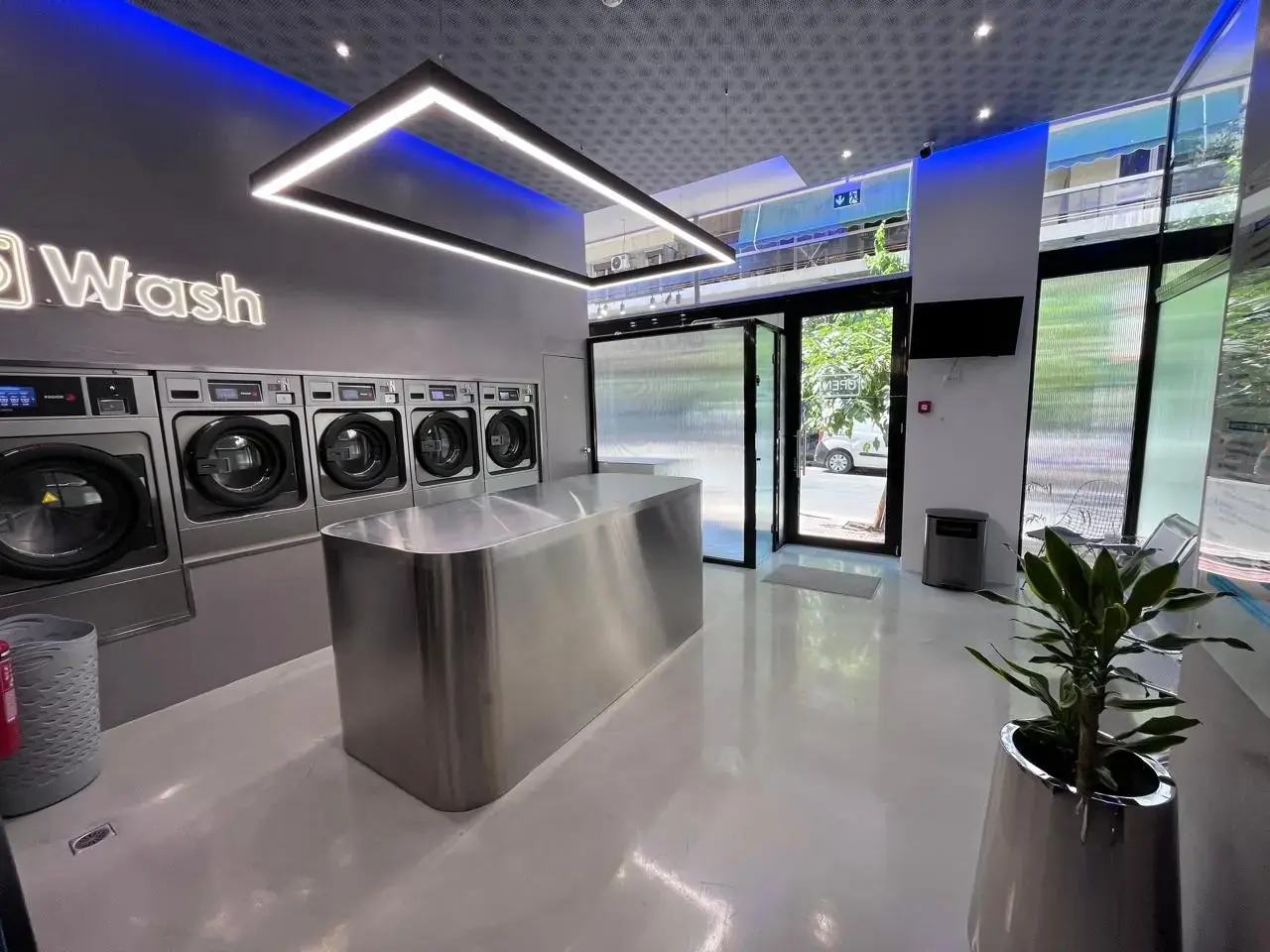 Το εσωτερικό του Laundromat με τον ανοξείδωτο πάγκο διπλώματος και τα πλυντήρια στον τοίχο