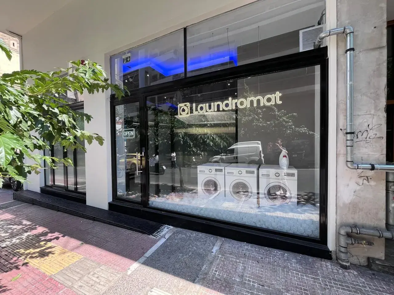 Η είσοδος και η βιτρίνα του Laundromat στην Ιουλιανού 50, στο ισόγειο της πολυκατοικίας