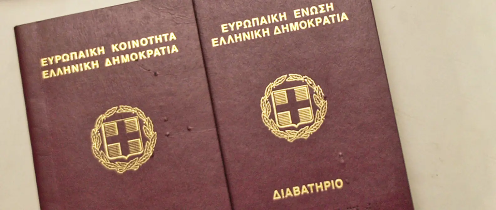 Zwei griechische Reisepässe nebeneinander, ein älterer und ein neuerer Einband, mit Wappen und goldener Schrift